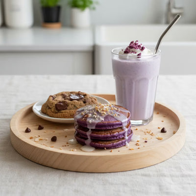 Purple ube pancakes with glaze, ube milkshake and chocolate chip cookie arranged on wooden serving board in modern kitchen Image